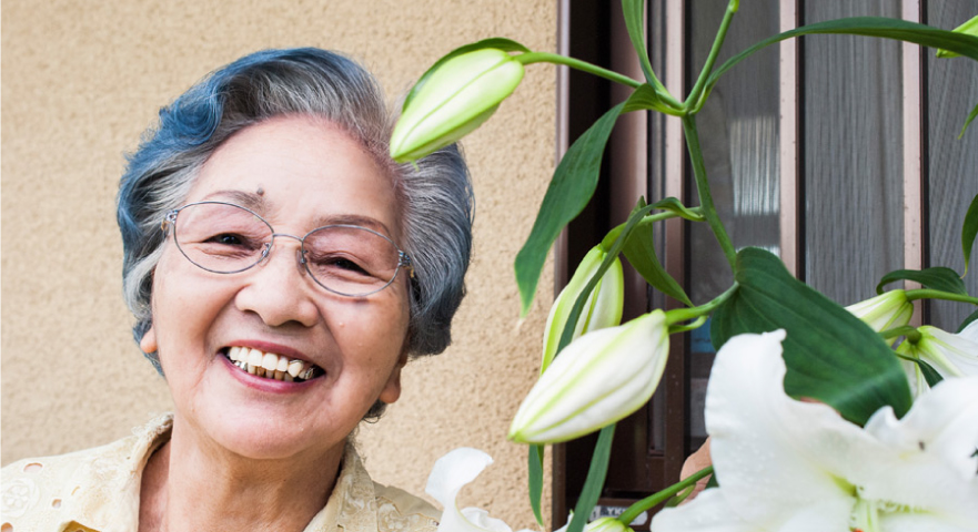 お年寄りが花の隣で微笑む姿